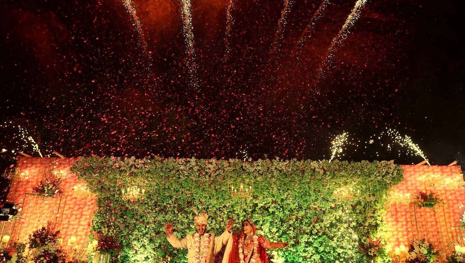 Bride and groom celebrating under fireworks and falling flower petals